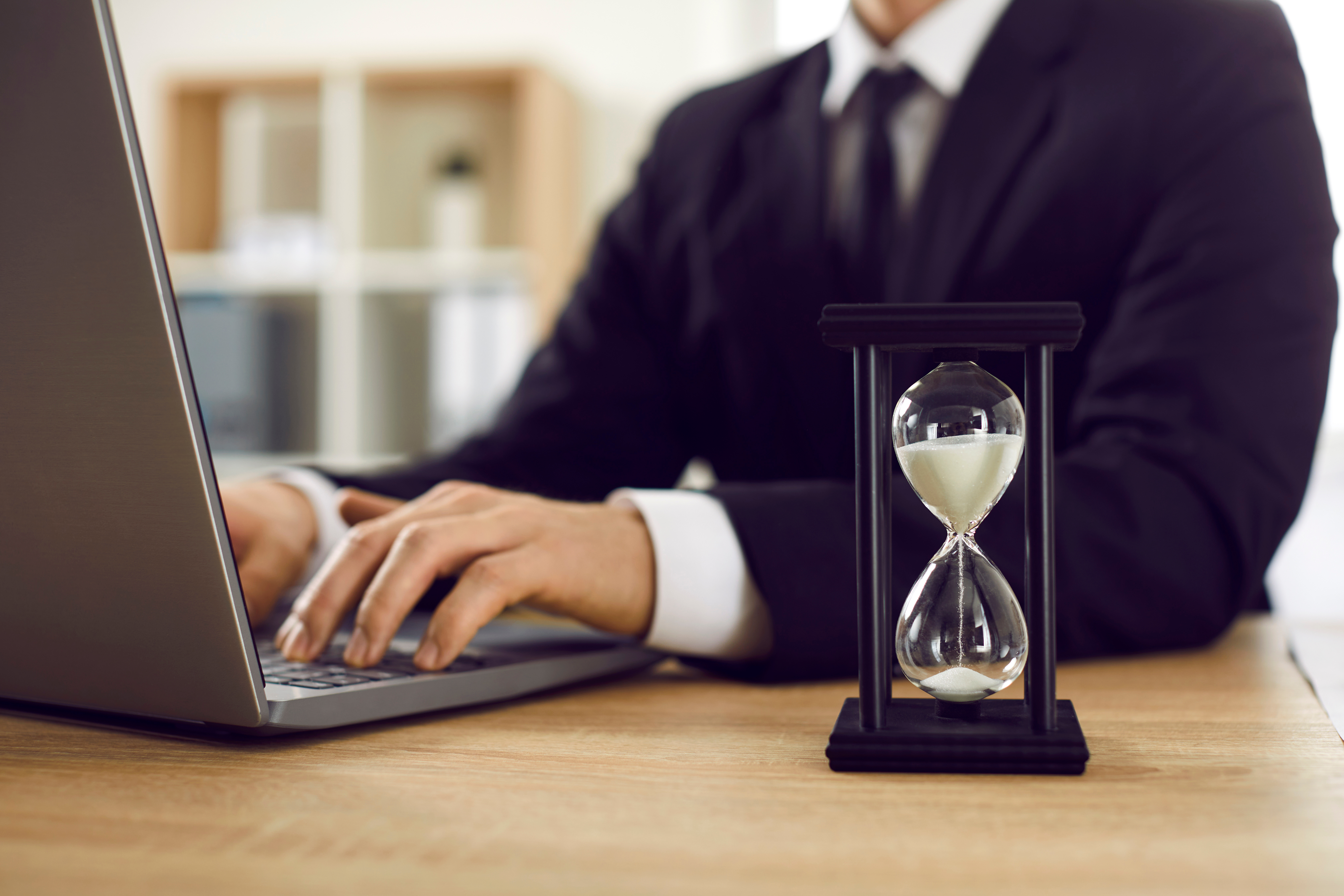 Zeitarbeiter vor Laptop mit Sanduhr.